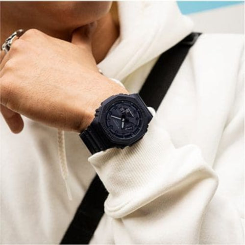 Person wearing a black wristwatch with a white jacket